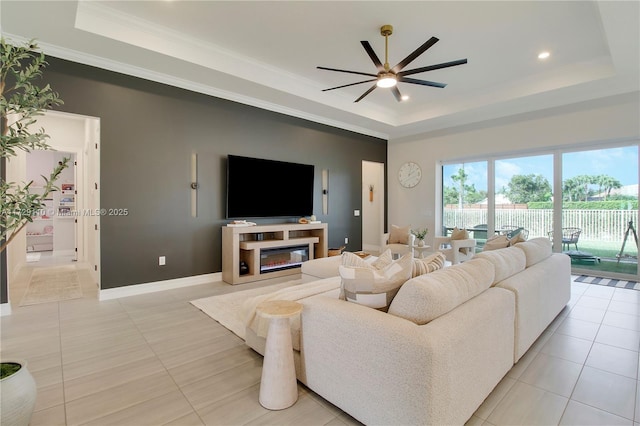 living room featuring ceiling fan, light tile patterned floors, crown molding, and a raised ceiling