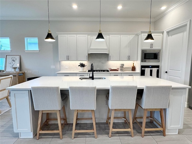 kitchen featuring sink, a center island with sink, stainless steel microwave, and oven