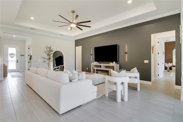 living room with a tray ceiling, crown molding, and light tile patterned floors