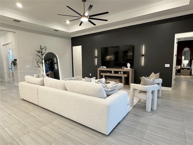 living room featuring ceiling fan, light tile patterned floors, a tray ceiling, and crown molding