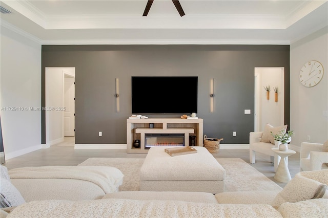 living room with a tray ceiling and ornamental molding