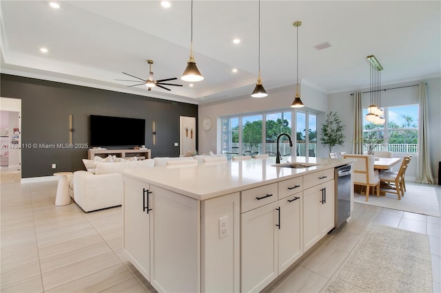 kitchen with sink, white cabinetry, hanging light fixtures, an island with sink, and a raised ceiling