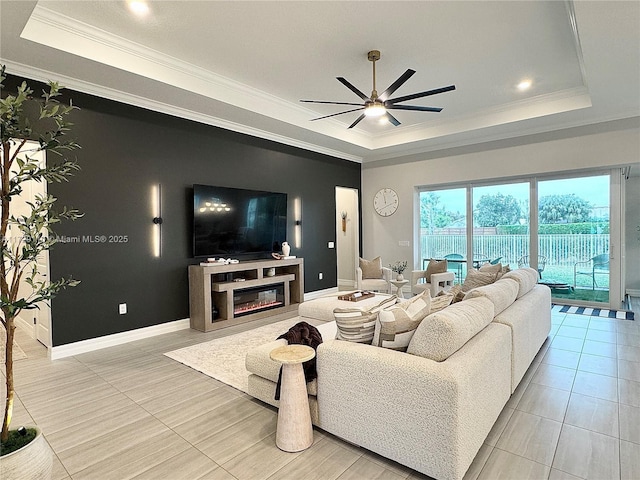 tiled living room with ceiling fan, a tray ceiling, and ornamental molding