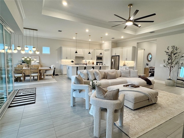 living room featuring ceiling fan, light tile patterned floors, a tray ceiling, and ornamental molding