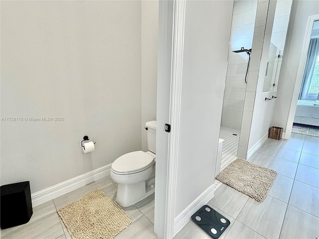 bathroom with a tile shower and toilet