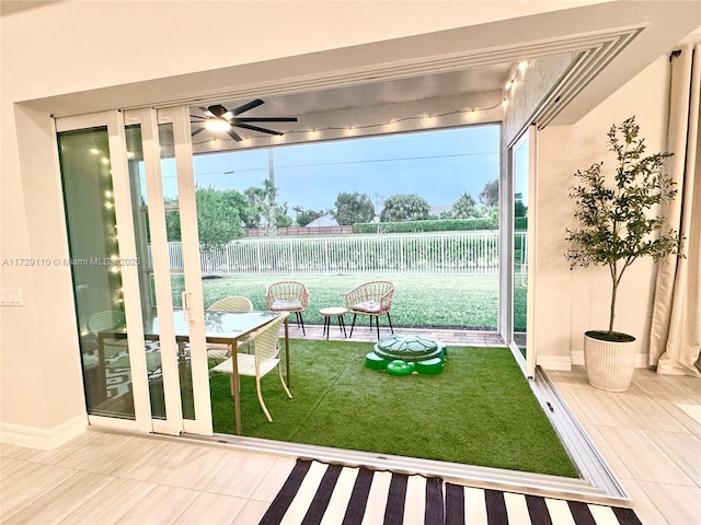 doorway to outside with ceiling fan and tile patterned flooring