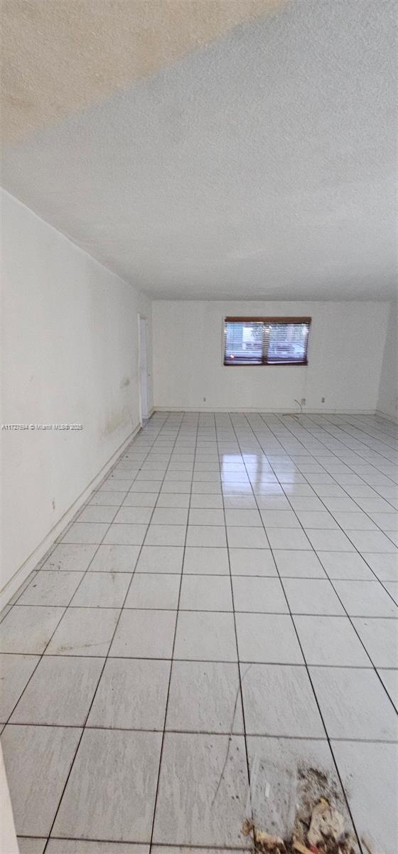 tiled empty room with a textured ceiling