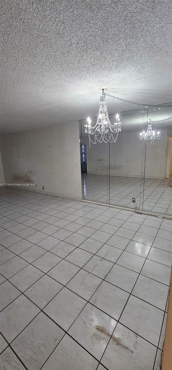 tiled empty room with an inviting chandelier