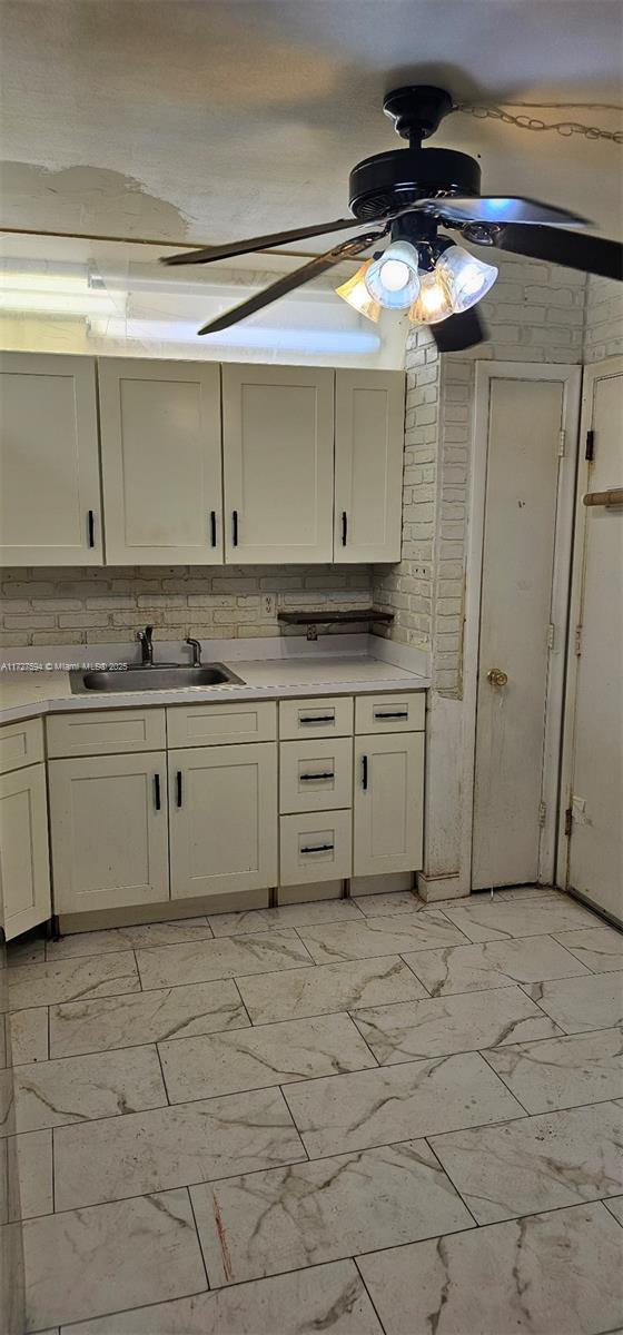 kitchen featuring ceiling fan, backsplash, and sink