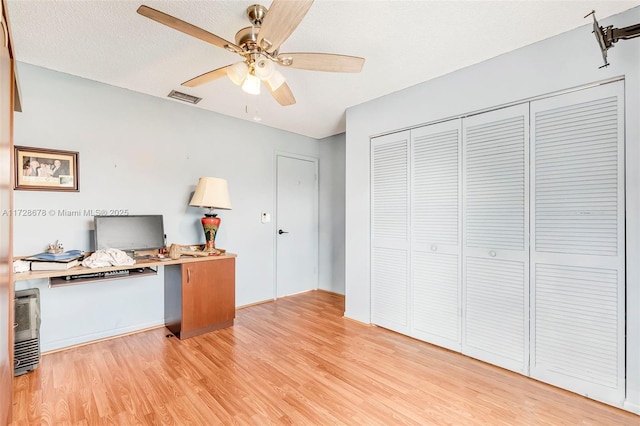 home office with ceiling fan, light hardwood / wood-style flooring, and a textured ceiling