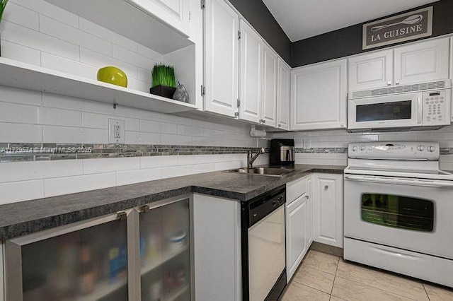 kitchen featuring white appliances, white cabinetry, decorative backsplash, sink, and light tile patterned floors