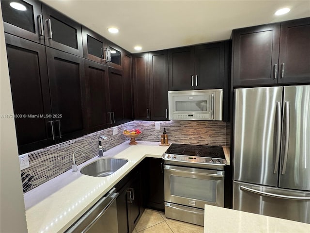 kitchen featuring appliances with stainless steel finishes, sink, light tile patterned floors, decorative backsplash, and dark brown cabinetry