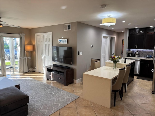 kitchen featuring a kitchen island, ceiling fan, a breakfast bar, and light tile patterned flooring