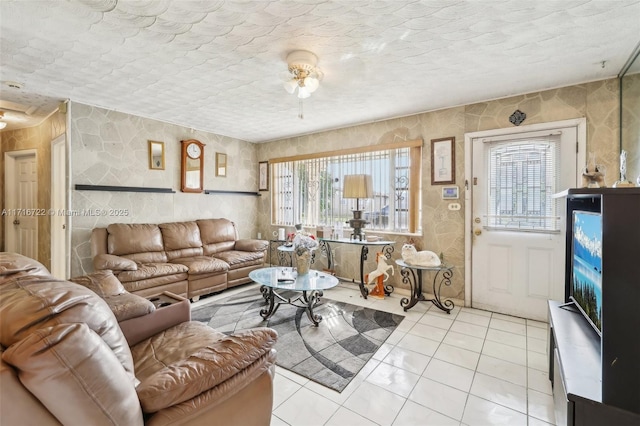 living room with ceiling fan, a textured ceiling, and light tile patterned flooring