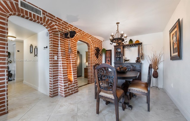 dining area featuring a notable chandelier and brick wall