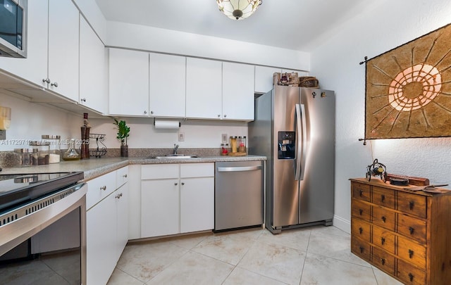 kitchen with white cabinetry, appliances with stainless steel finishes, sink, and light tile patterned floors