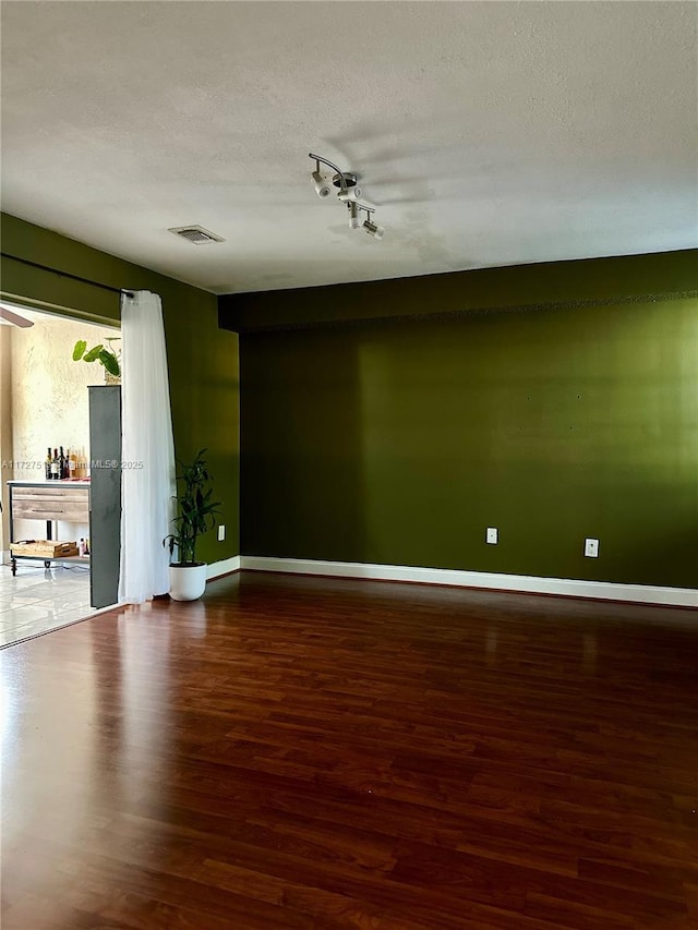 unfurnished room with hardwood / wood-style floors and a textured ceiling