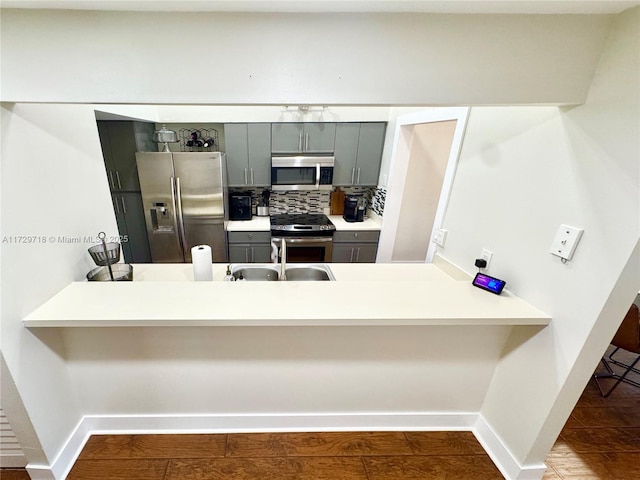 kitchen with tasteful backsplash, gray cabinetry, sink, kitchen peninsula, and stainless steel appliances