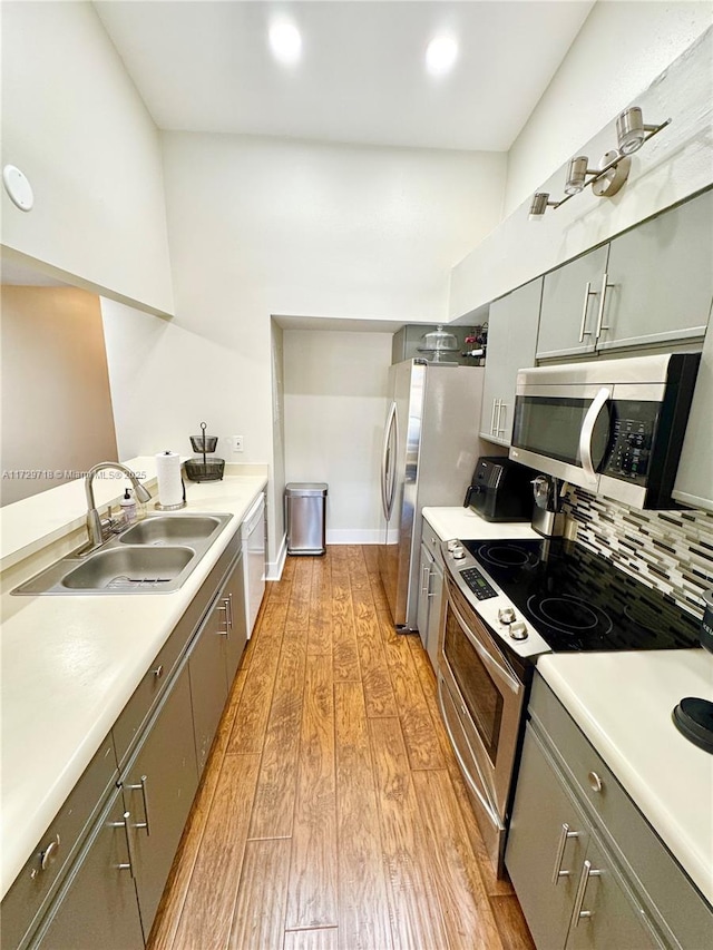 kitchen with light hardwood / wood-style floors, sink, appliances with stainless steel finishes, and tasteful backsplash