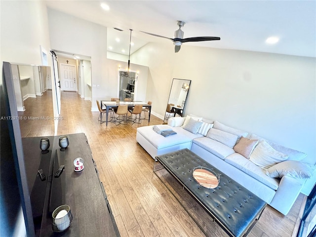 living room featuring wood-type flooring, high vaulted ceiling, and ceiling fan