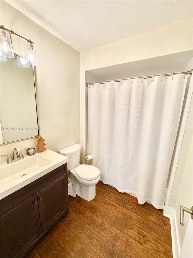 bathroom with hardwood / wood-style flooring, toilet, and vanity