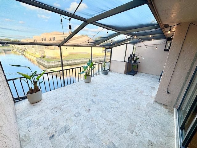 view of patio / terrace featuring glass enclosure and a water view