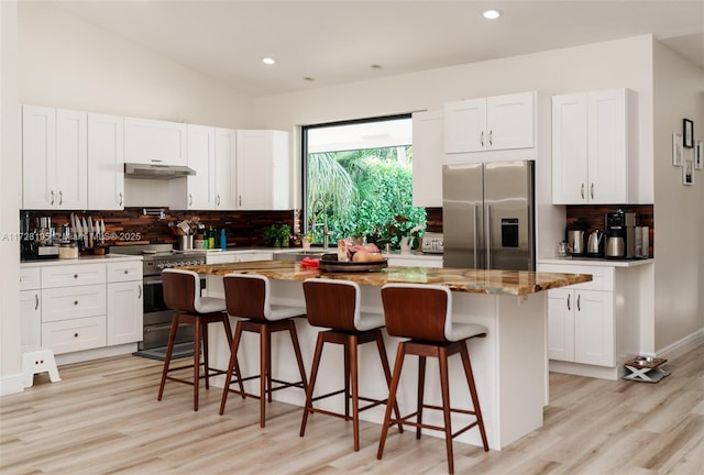 kitchen with high quality appliances, white cabinets, a breakfast bar area, and a kitchen island