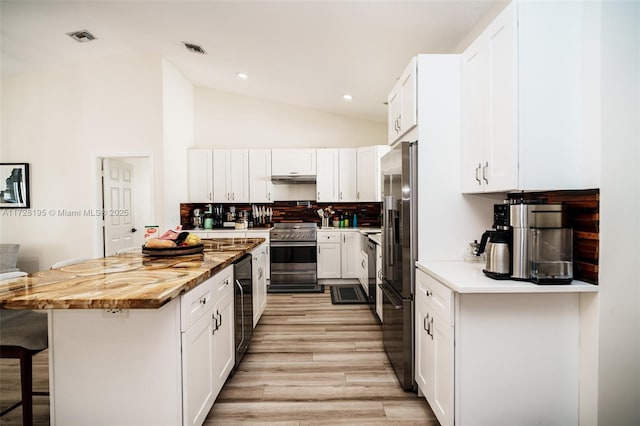 kitchen with premium appliances, white cabinets, a kitchen island, tasteful backsplash, and a kitchen breakfast bar