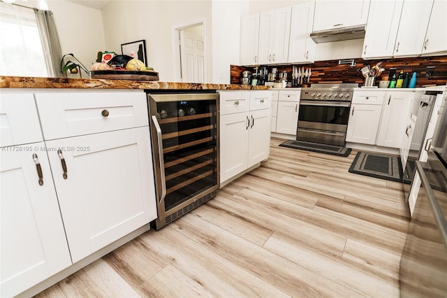 kitchen with stainless steel electric stove, backsplash, white cabinetry, light wood-type flooring, and beverage cooler