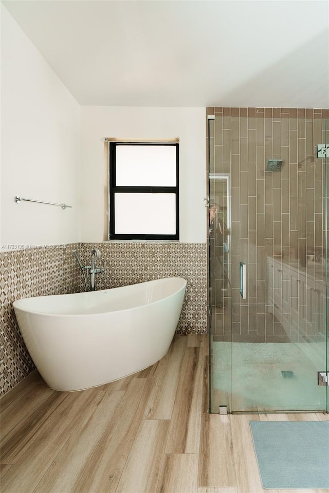 bathroom with plus walk in shower, hardwood / wood-style flooring, and tile walls