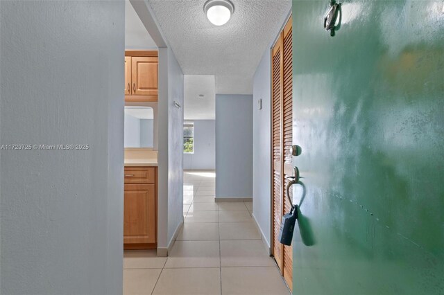 hall featuring light tile patterned floors and a textured ceiling