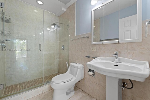 bathroom with tile patterned flooring, walk in shower, tile walls, and toilet