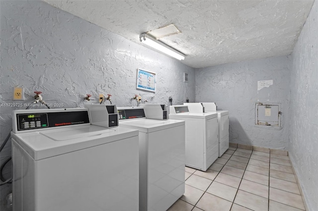 washroom featuring washing machine and clothes dryer, a textured ceiling, and light tile patterned floors