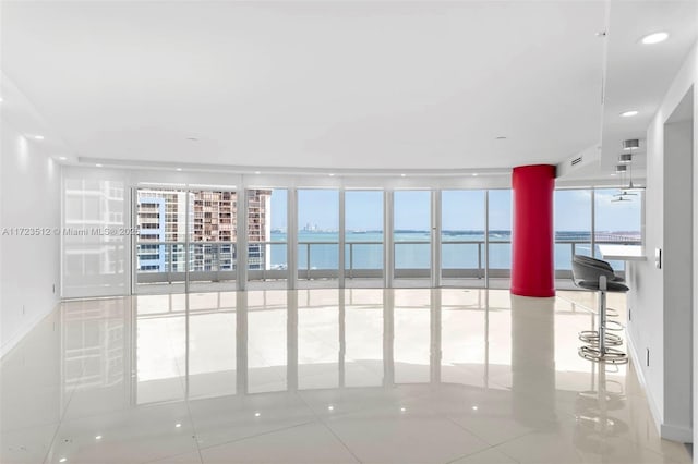 unfurnished room featuring floor to ceiling windows, a water view, and light tile patterned flooring