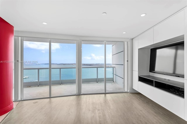 unfurnished living room featuring hardwood / wood-style flooring and a water view