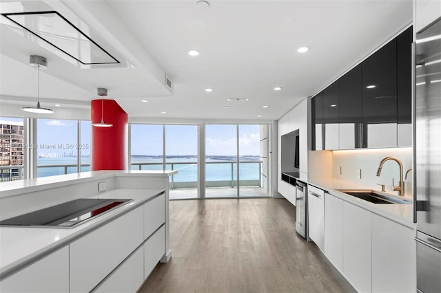 kitchen featuring sink, a water view, white cabinets, and pendant lighting