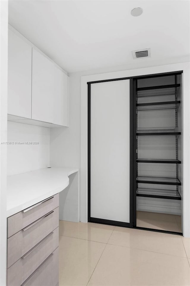 interior space featuring white cabinets and light tile patterned flooring