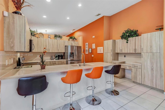 kitchen featuring light brown cabinetry, a kitchen breakfast bar, appliances with stainless steel finishes, and sink