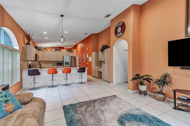 kitchen featuring a breakfast bar, light brown cabinets, stainless steel appliances, and light tile patterned flooring