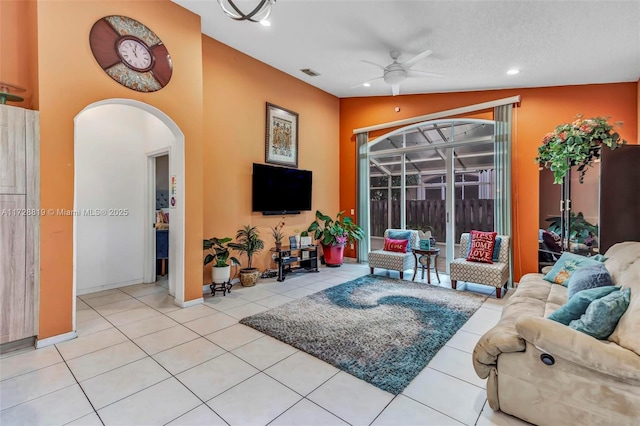 living room featuring a textured ceiling, ceiling fan, light tile patterned floors, and lofted ceiling