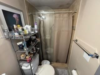 bathroom with toilet and a shower with shower curtain