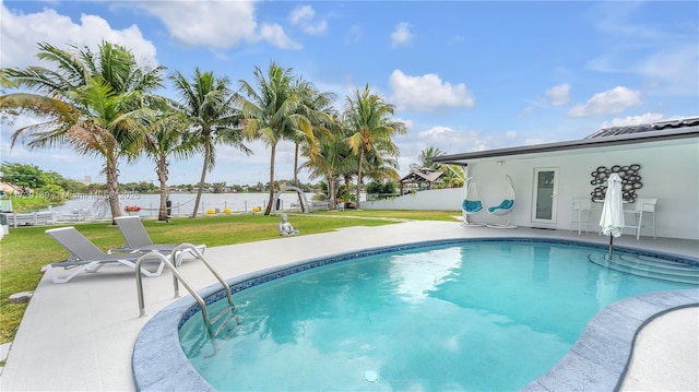 view of swimming pool featuring a water view, a yard, and a patio