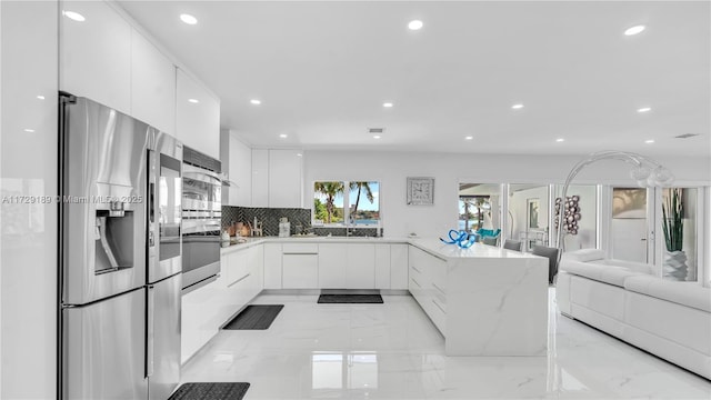 kitchen featuring white cabinetry, stainless steel appliances, tasteful backsplash, light stone countertops, and sink