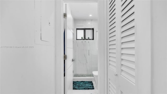 bathroom featuring toilet and a shower with door