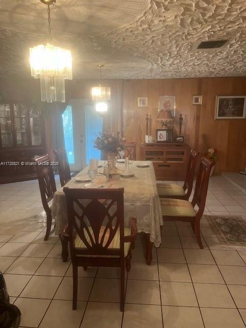 tiled dining space with a notable chandelier and wooden walls