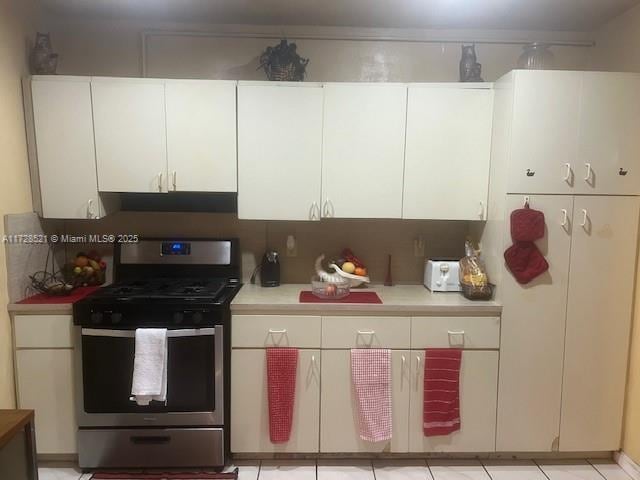 kitchen with light tile patterned floors, stainless steel range with gas cooktop, and white cabinets