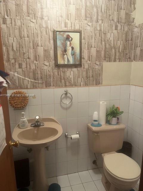 bathroom with tile patterned flooring, sink, tile walls, and toilet