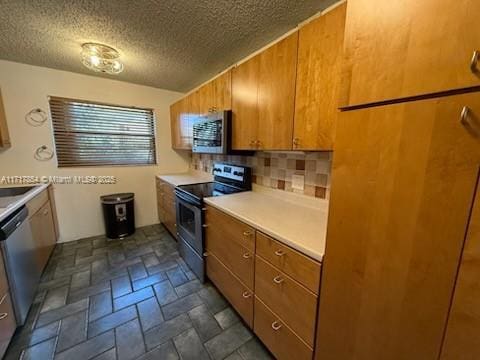 kitchen with a textured ceiling, appliances with stainless steel finishes, and decorative backsplash