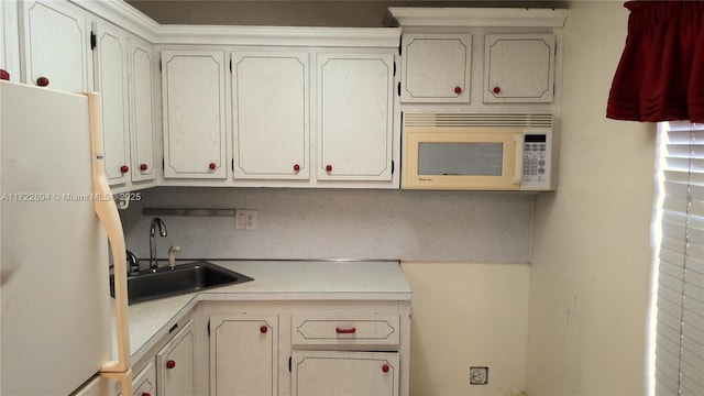 kitchen with sink, white appliances, and white cabinets