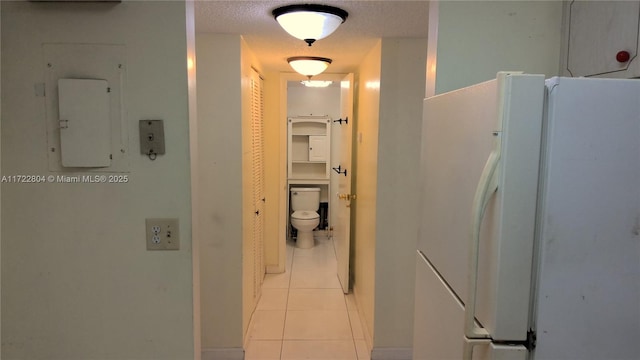 hallway with light tile patterned flooring, electric panel, and a textured ceiling